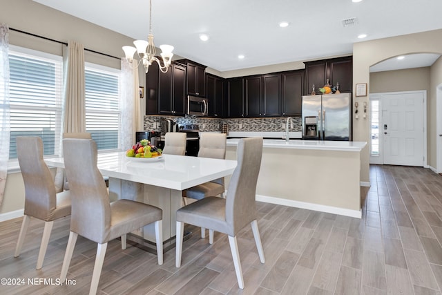 kitchen featuring appliances with stainless steel finishes, hanging light fixtures, light hardwood / wood-style flooring, and plenty of natural light