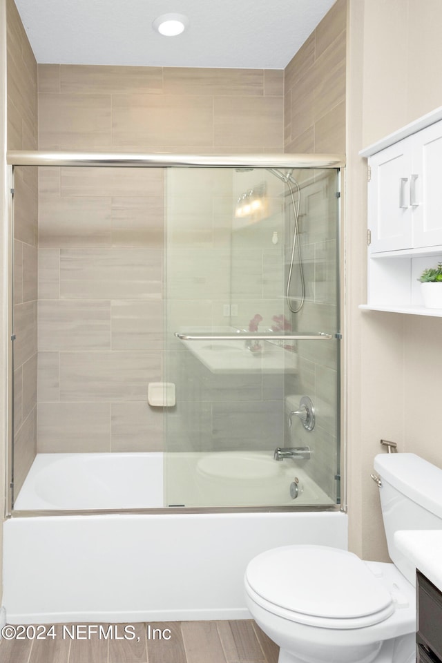 full bathroom featuring vanity, hardwood / wood-style floors, toilet, and shower / bath combination with glass door