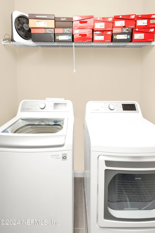 laundry area with washing machine and clothes dryer and hardwood / wood-style flooring