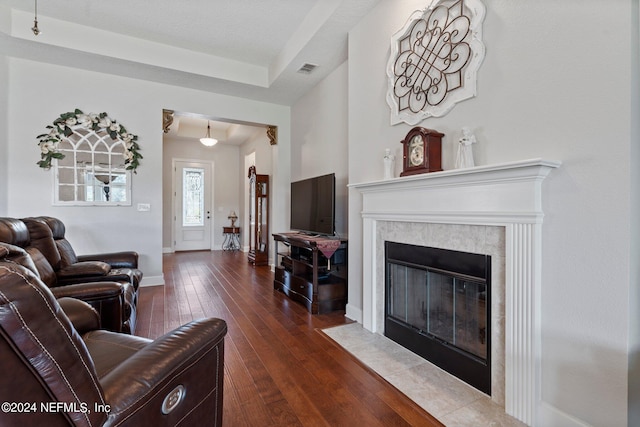 living room with a premium fireplace, a textured ceiling, and dark hardwood / wood-style flooring