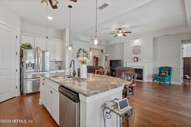 kitchen featuring appliances with stainless steel finishes, white cabinetry, a kitchen island with sink, and sink