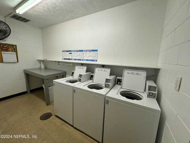 clothes washing area with independent washer and dryer and a textured ceiling