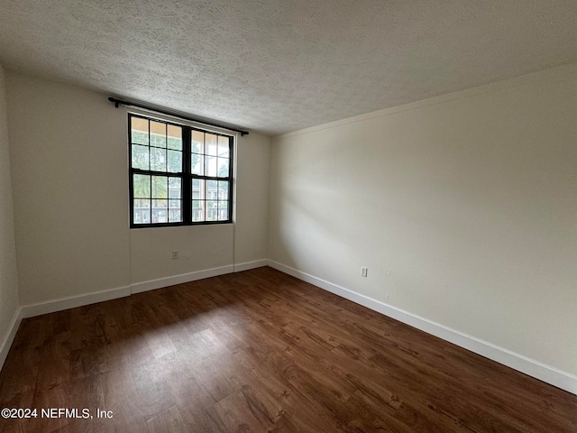 empty room featuring a textured ceiling and dark hardwood / wood-style floors