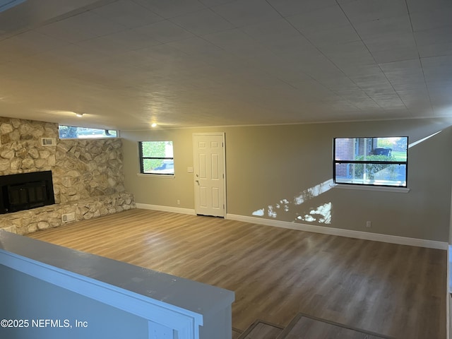 unfurnished living room featuring hardwood / wood-style floors and a stone fireplace