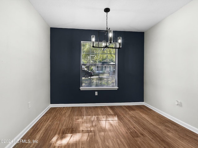 unfurnished dining area featuring an inviting chandelier and hardwood / wood-style flooring