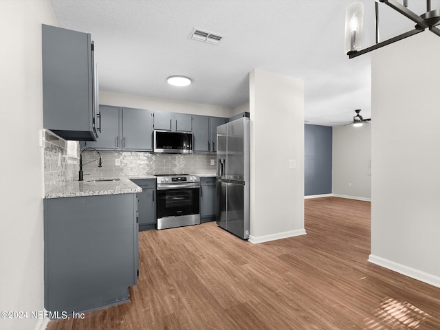 kitchen with gray cabinetry, sink, light wood-type flooring, a textured ceiling, and stainless steel appliances