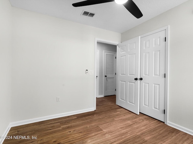 unfurnished bedroom with a closet, a textured ceiling, wood-type flooring, and ceiling fan