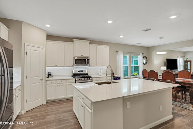 kitchen with white cabinetry, sink, light hardwood / wood-style floors, and appliances with stainless steel finishes