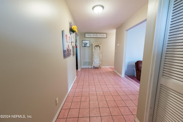 hall with light tile patterned flooring and a textured ceiling