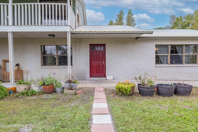 property entrance featuring a yard and a balcony