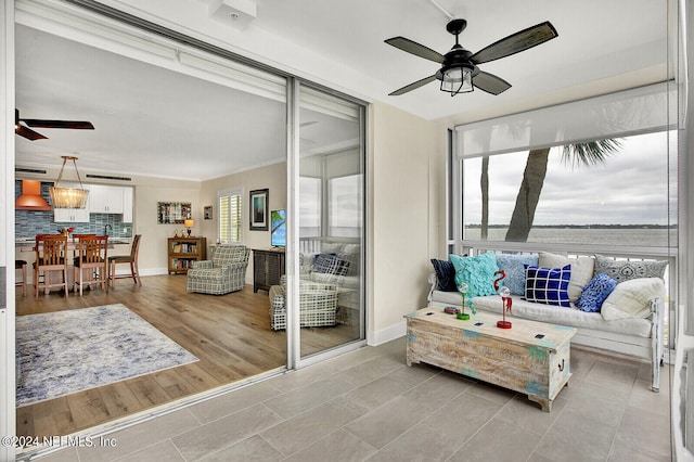 tiled living area with baseboards and ceiling fan