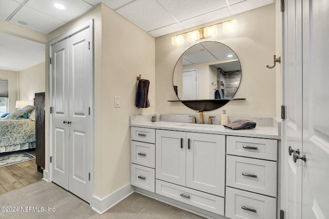 bathroom featuring tile patterned flooring, vanity, ensuite bath, baseboards, and a paneled ceiling
