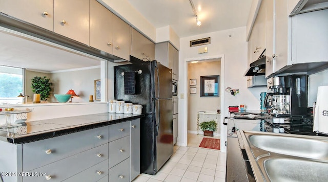 kitchen featuring gray cabinetry, light tile patterned floors, track lighting, and black fridge