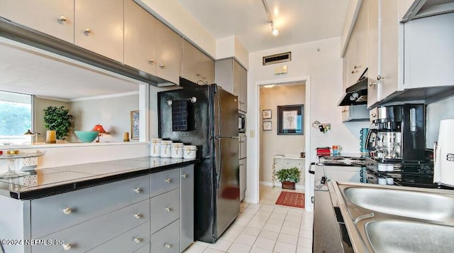 kitchen with dark countertops, visible vents, freestanding refrigerator, gray cabinets, and under cabinet range hood