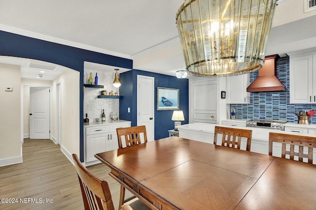 dining area with visible vents, a bar, light wood-type flooring, crown molding, and baseboards