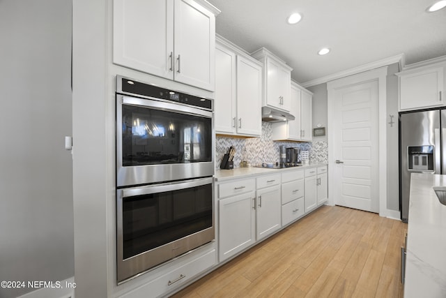 kitchen with appliances with stainless steel finishes, crown molding, white cabinets, and light hardwood / wood-style floors