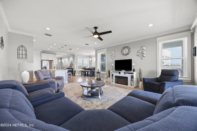 living room featuring crown molding, hardwood / wood-style flooring, and ceiling fan with notable chandelier