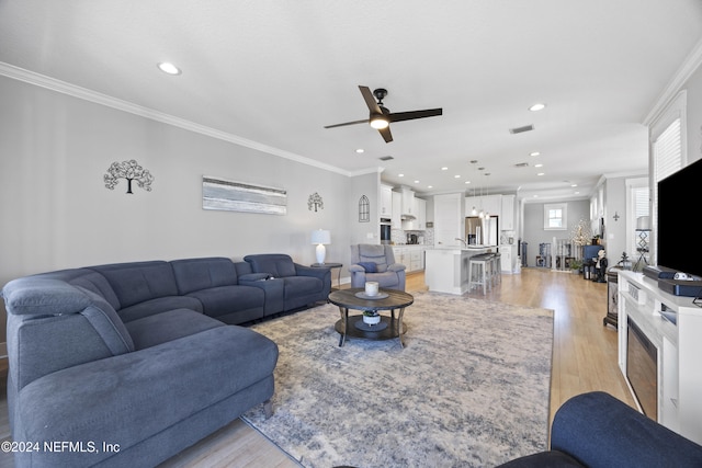 living room featuring crown molding, light wood-type flooring, and ceiling fan