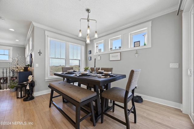 dining space featuring crown molding, a textured ceiling, light wood-type flooring, and a wealth of natural light