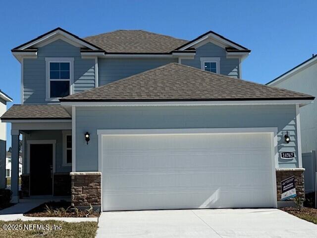 view of front of property with driveway, a shingled roof, and an attached garage