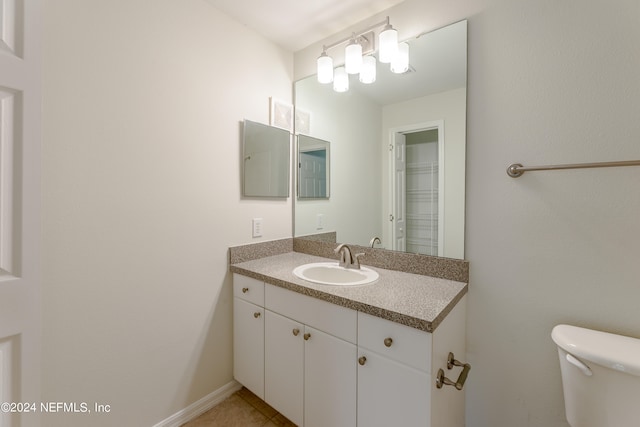 bathroom with toilet, vanity, and tile patterned flooring