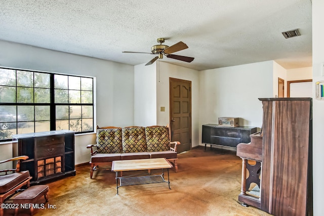 living room with ceiling fan, carpet flooring, and a textured ceiling