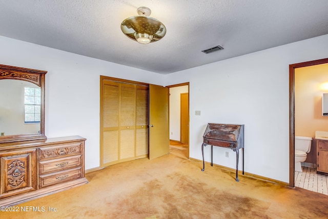 bedroom with a closet, light carpet, and a textured ceiling