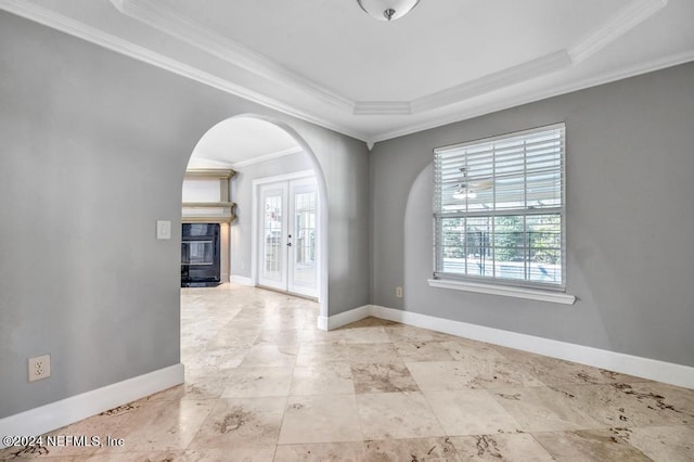 empty room featuring french doors, crown molding, a tray ceiling, and plenty of natural light