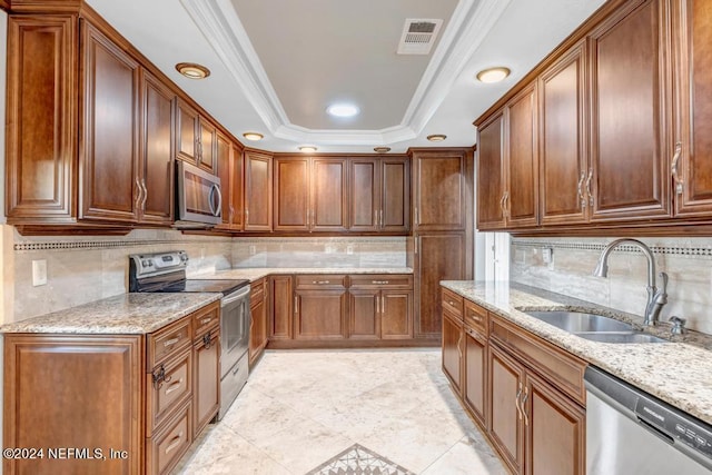 kitchen with stainless steel appliances, ornamental molding, sink, and a raised ceiling