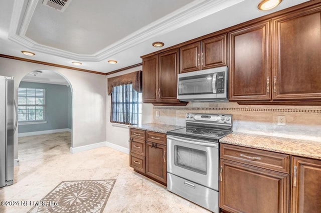 kitchen featuring appliances with stainless steel finishes, crown molding, light stone countertops, and backsplash