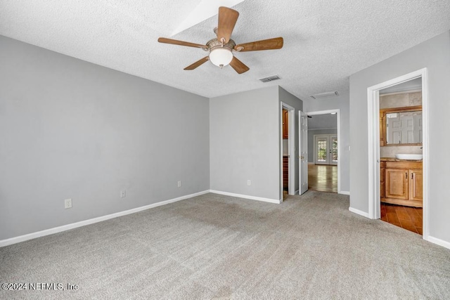 unfurnished living room with light carpet, a textured ceiling, and ceiling fan