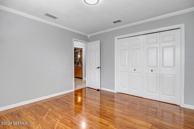 unfurnished bedroom with a closet, crown molding, and light hardwood / wood-style flooring