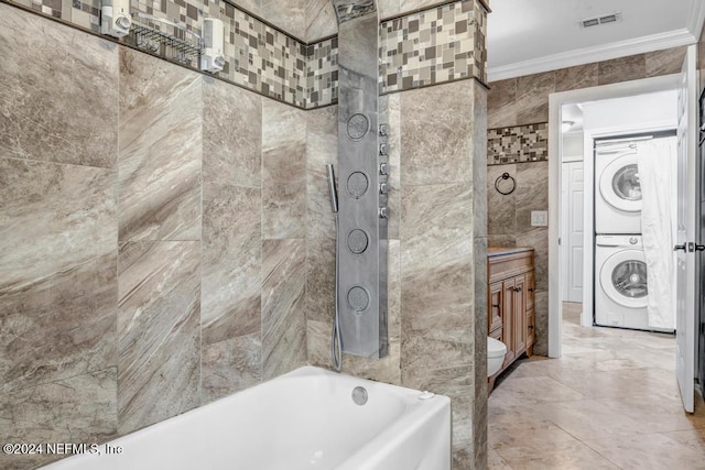 full bathroom featuring shower with separate bathtub, tile walls, vanity, crown molding, and stacked washer / dryer