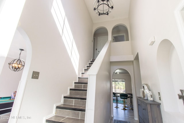 staircase featuring a notable chandelier, a high ceiling, and hardwood / wood-style floors