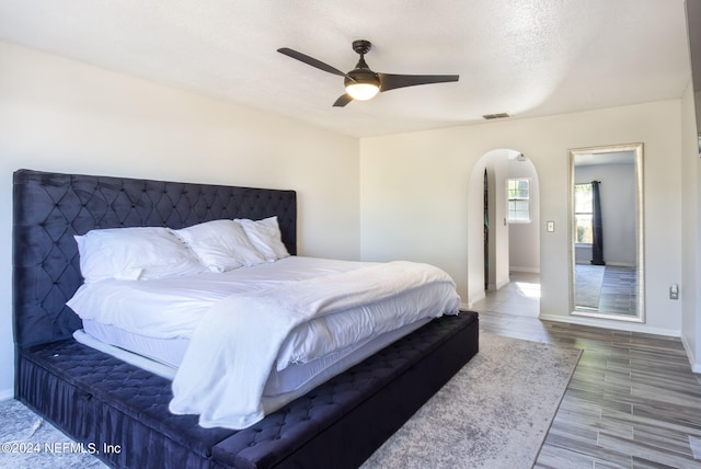 bedroom with a textured ceiling, hardwood / wood-style flooring, and ceiling fan