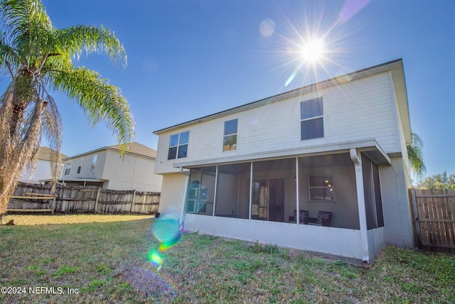 rear view of property with a sunroom and a lawn