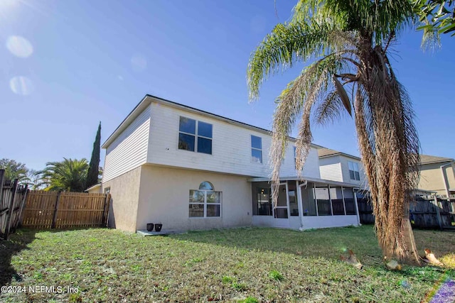 back of property with a yard and a sunroom