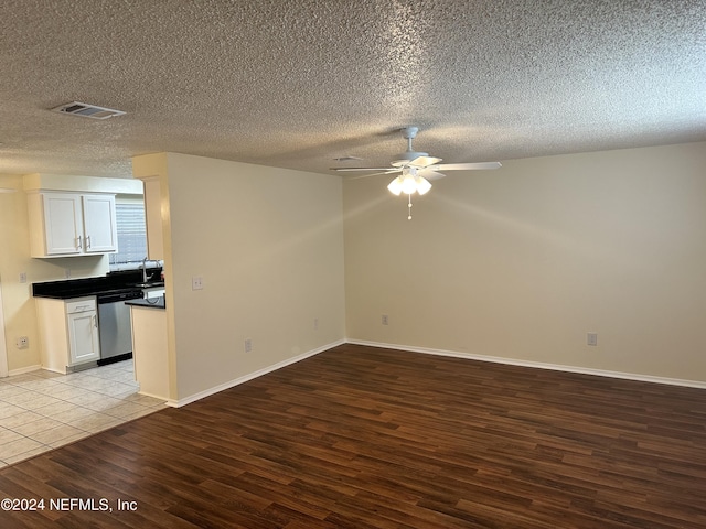 unfurnished living room featuring ceiling fan, light wood-type flooring, and a textured ceiling