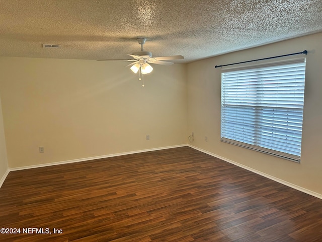 empty room featuring ceiling fan, dark wood-type flooring, and a textured ceiling