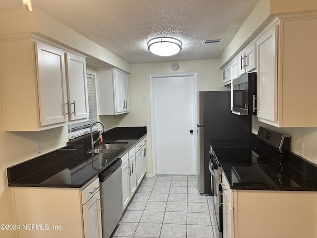 kitchen featuring white cabinets, sink, a textured ceiling, appliances with stainless steel finishes, and light tile patterned flooring