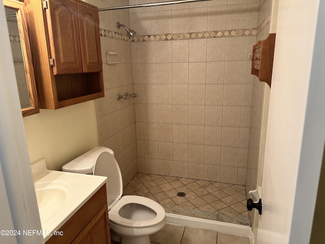 bathroom with tile patterned flooring, vanity, tiled shower, and toilet