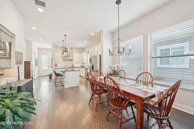 dining area with dark wood-type flooring and an inviting chandelier