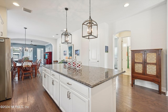 kitchen with dark hardwood / wood-style floors, white cabinets, a kitchen island, and stainless steel refrigerator