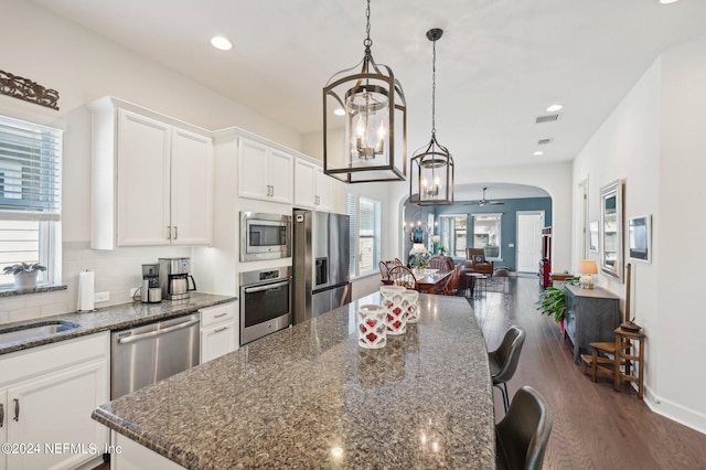 kitchen featuring white cabinets, dark stone countertops, stainless steel appliances, and dark wood-type flooring