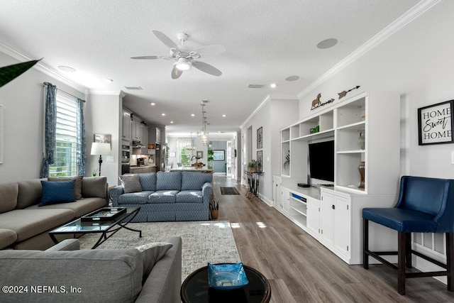 living room featuring ornamental molding, hardwood / wood-style floors, a textured ceiling, and ceiling fan with notable chandelier