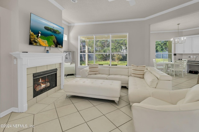 living room with a tiled fireplace, crown molding, light tile patterned floors, a chandelier, and a textured ceiling