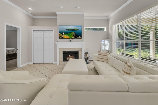 living room with crown molding, a textured ceiling, a tiled fireplace, and light tile patterned floors