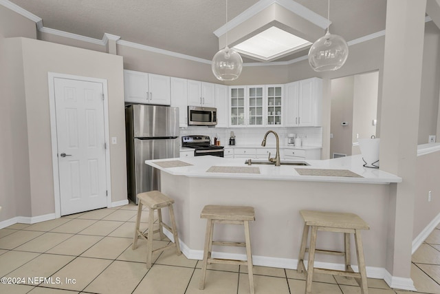 kitchen featuring white cabinets, a kitchen bar, sink, decorative light fixtures, and stainless steel appliances