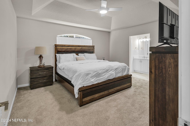 bedroom featuring ceiling fan, a textured ceiling, ensuite bathroom, and light colored carpet