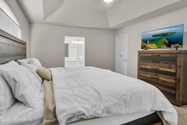 carpeted bedroom with ensuite bathroom and a raised ceiling